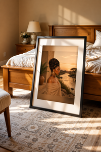At The River Black woman portrait in a black frame leaning against a wooden bed in a cozy bedroom