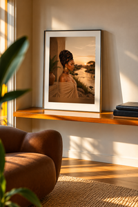 At The River print on a wooden shelf: Black woman in a headwrap beside a river at golden-hour sunset